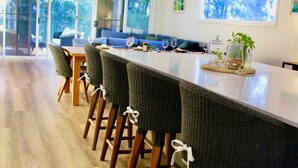 Une cuisine moderne dotée d’un grand îlot central, de tabourets de bar et d’une table à manger.