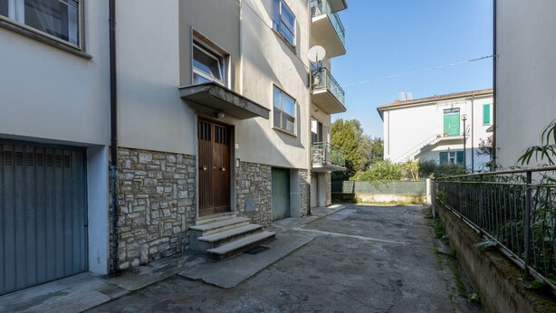Un edificio residencial con fachada de piedra, puerta de madera y un balcón.