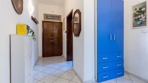 Un pasillo con un armario azul, una puerta de madera, un armario blanco y un cuadro enmarcado en la pared.