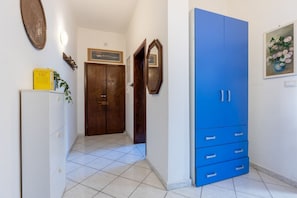A hallway with a blue wardrobe, a wooden door, a white cabinet, and a framed picture on the wall.