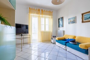 A living room with a sofa, television, and artwork on the wall.