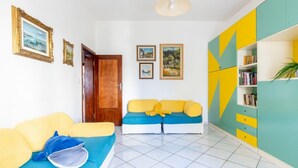 Una habitación con sofá, estantería y puerta.