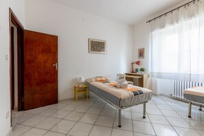 A bedroom with a bed, a desk, a chair, a radiator, and a door.