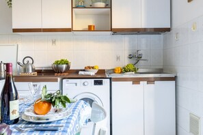 A compact kitchen with a dishwasher, a sink, and a countertop with various items.