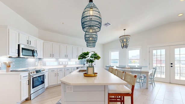 A modern kitchen with white cabinetry, a central island, stainless steel appliances, and pendant lighting. - PP627 Private Heated Pool, Golf Cart Included, Parking for 6 (Port Aransas)