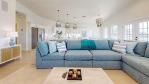 A spacious living room with a large sectional sofa, a coffee table, and a kitchen in the background. - PP627 Private Heated Pool, Golf Cart Included, Parking for 6 (Port Aransas)