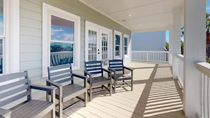 A covered porch with wooden benches and white railings, overlooking a body of water. - PP627 Private Heated Pool, Golf Cart Included, Parking for 6 (Port Aransas)