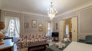 Una habitación de hotel con sofá, cama, televisor y candelabro.