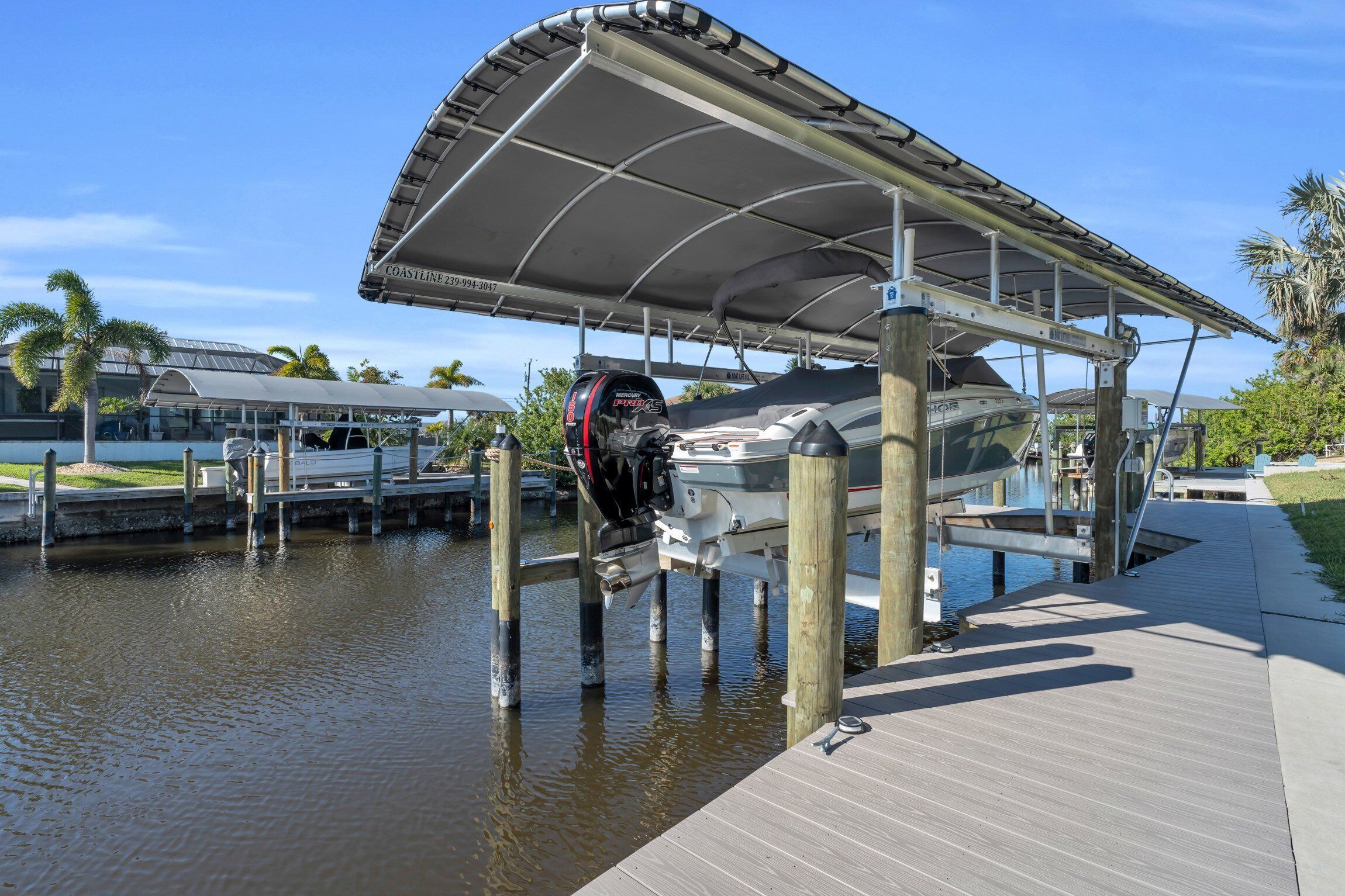 A boat docked under a covered area with a canopy, connected to a wooden dock over water.