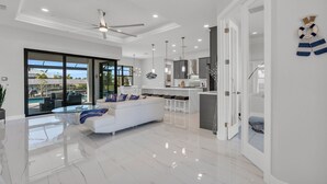Una sala de estar moderna con un sofá blanco, una mesa de centro de vidrio y vistas a una piscina.