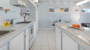 Een moderne keuken met witte kasten, een gasfornuis, een magnetron en een spoelbak.