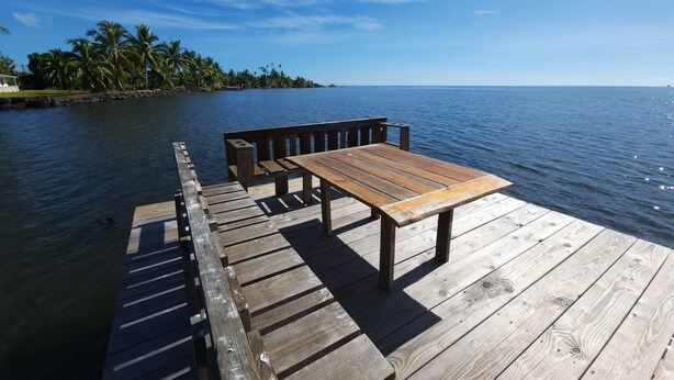 Un muelle de madera que se adentra en aguas tranquilas, con una banca y una mesa.