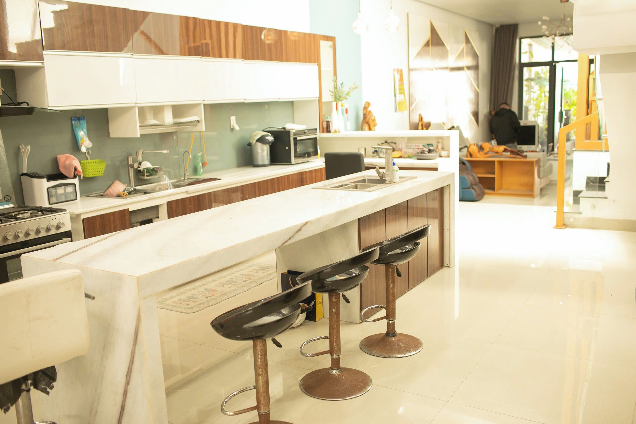 A modern kitchen with a central island, bar stools, and a dining area with a wooden table and chairs.