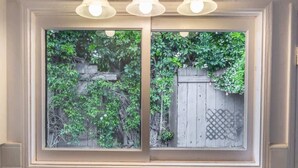 Eine Küche mit einem doppelten Spülbecken, einem Fenster mit Blick ins Grüne und einer Lampe über dem Spülbecken.