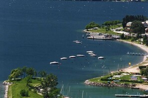 A marina with boats docked, a pier, and a small island with greenery. - Villa Sunrise with pool and large private garden - few step from the beach  (Dervio)