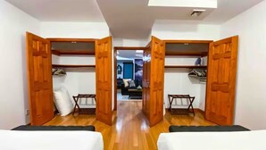 Una camera d'albergo con due letti, armadi in legno e un corridoio che porta al bagno.