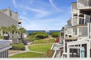 A coastal residential area with a view of the ocean, featuring houses with balconies and a pathway leading to the beach.