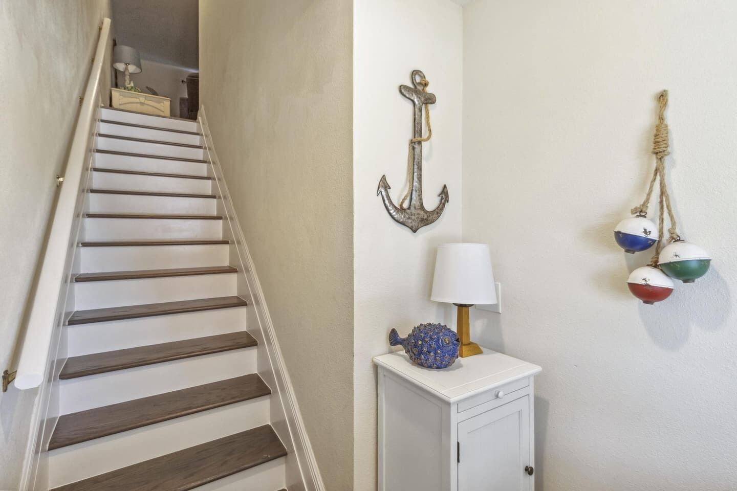 Una escalera con escalones de madera y una pared blanca decorada con motivos náuticos.