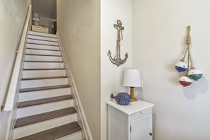 Eine Treppe mit Holzboden und einer weißen Wand mit maritimer Dekoration.