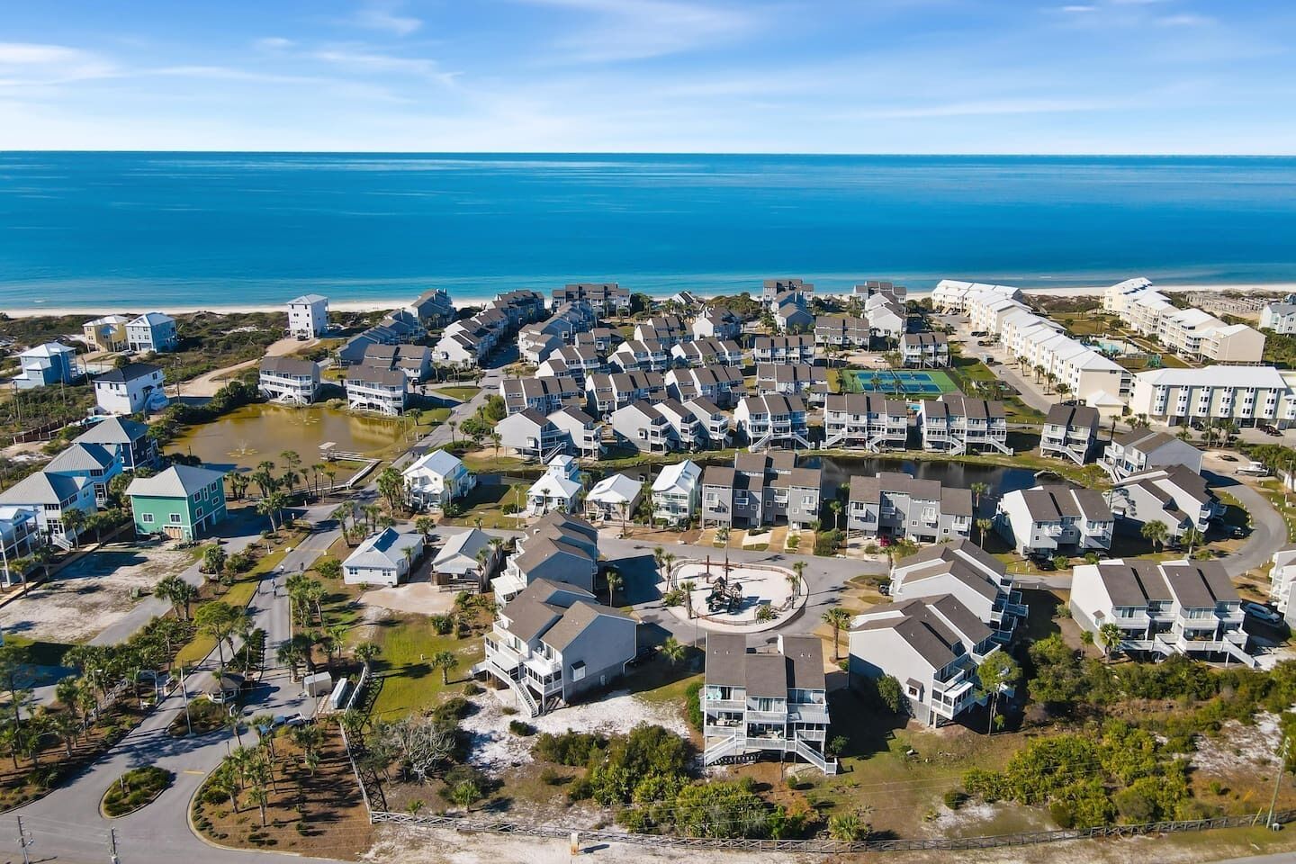 A coastal residential area with houses, a beach, and a clear view of the ocean.