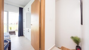 Et moderne soveværelse med seng, garderobe og en lille plantepotte.