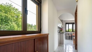 Corredor com armário de madeira, janela e vista para uma cozinha.