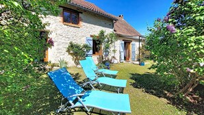 A stone house with a tiled roof, a small garden, and blue lounge chairs. - Vacation home Durand by Interhome (Saint Chamarand)