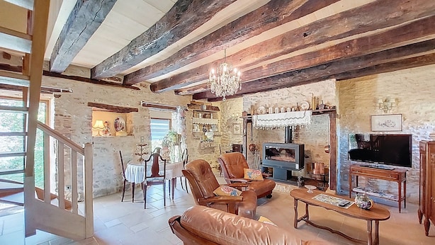 A rustic interior with exposed wooden beams, a chandelier, a fireplace, and a television. - Vacation home Durand by Interhome (Saint Chamarand)