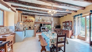 A rustic kitchen with exposed beams, a stone wall, and a dining area with a wooden bench and table. - Vacation home Durand by Interhome (Saint Chamarand)