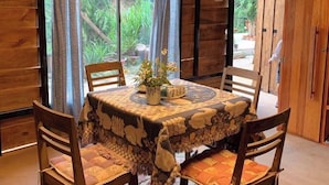 Ein Essbereich aus Holz mit einem Tisch, der mit einer gemusterten Tischdecke bedeckt ist, umgeben von vier Holzstühlen.