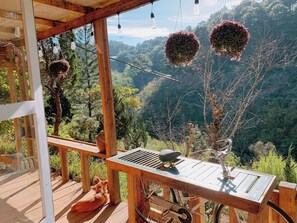 A wooden deck with a bicycle, a table, and hanging light bulbs. - Homestay Sound of Silence (Xuan Huong - Da Lat)