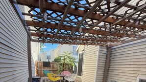 A backyard with a grill, patio furniture, and an air conditioning unit.