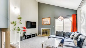 A modern living room with a grey sofa, a coffee table, a TV, and a fireplace.