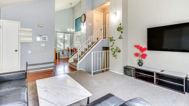 A spacious living area with a staircase, a flat-screen TV, and a dining table.