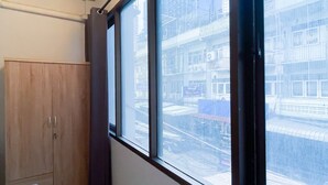 A room with a large window, a wooden wardrobe, and a view of a cityscape. - MAXi MaMa Room (Bangkok)