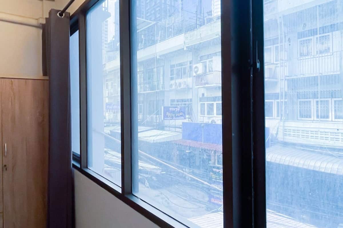 Une pièce dotée d’une grande fenêtre, d’une armoire en bois et offrant une vue sur le paysage urbain.