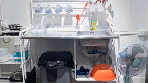 A compact kitchen with a sink, a fan, and a trash bin. - MAXi MaMa Room (Bangkok)
