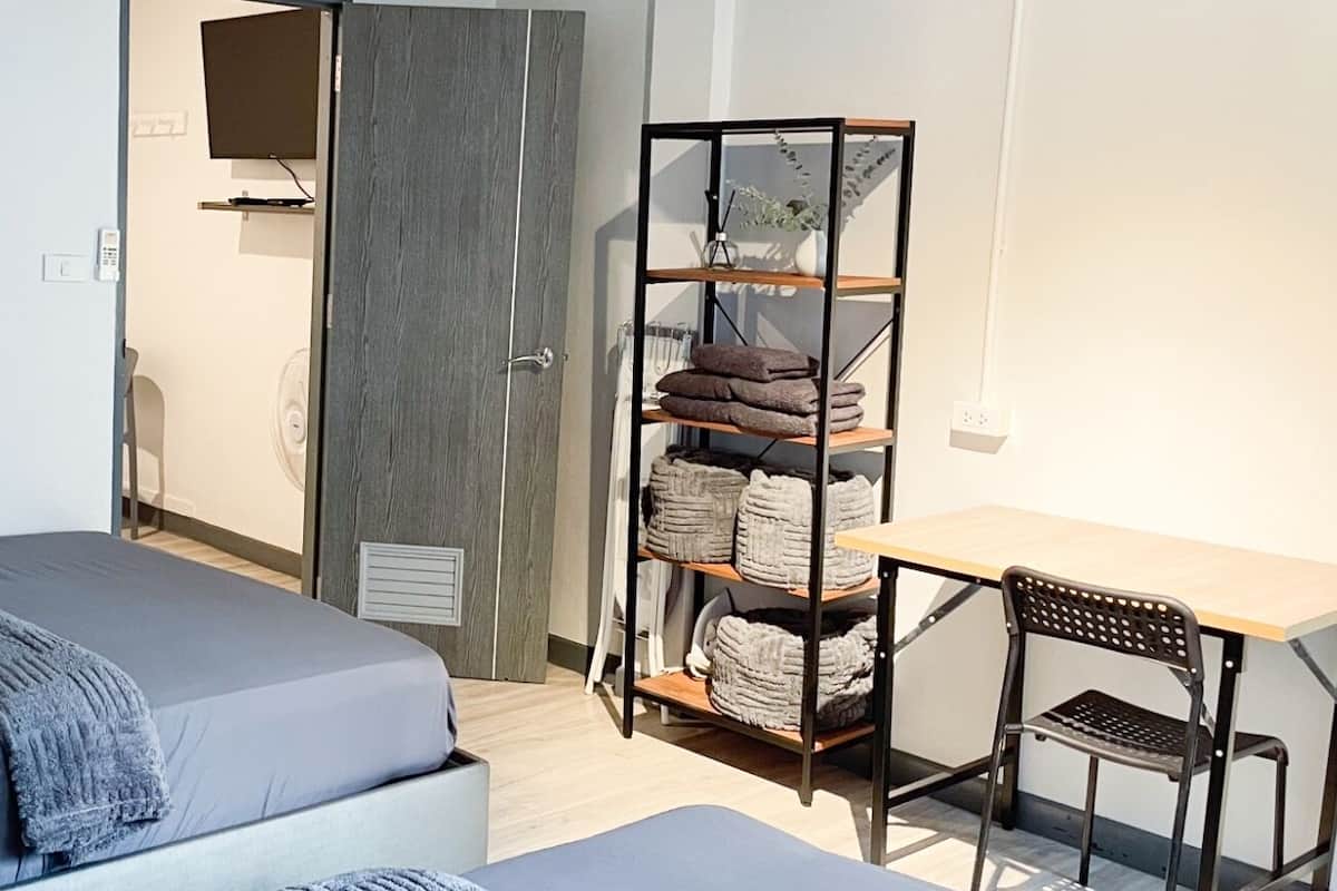 Une chambre avec un lit, un bureau et une étagère où sont rangées des serviettes.