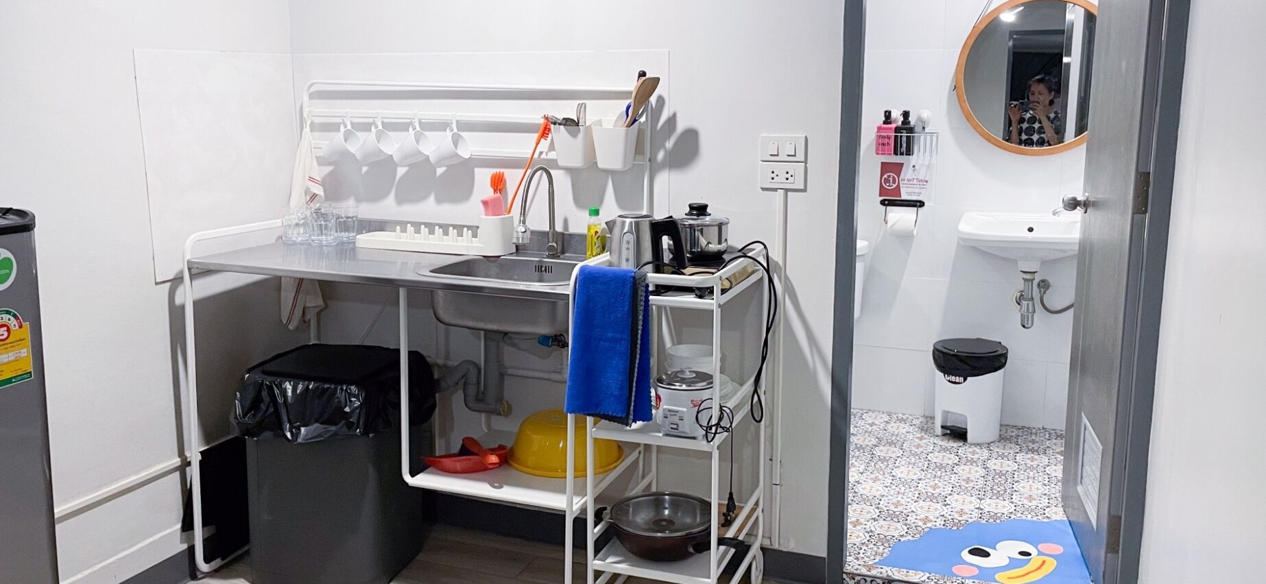 Una kitchenette compacta con lavamanos, estufa y estanterías.