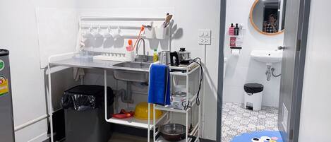 Una kitchenette compacta con lavamanos, estufa y estanterías.