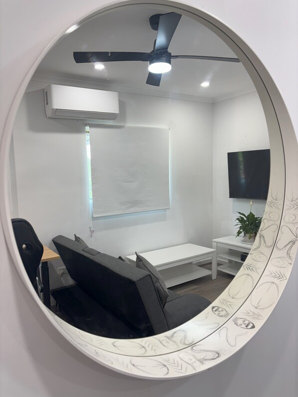 A conference room with a whiteboard, a flat-screen TV, a ceiling fan, and a round mirror with a decorative frame. - Sunflower Homes: Peace and Joy (Para Hills)