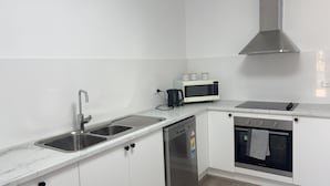 A modern kitchen with white cabinetry, stainless steel appliances, and a marble countertop. - Peace and Joy (Para Hills)