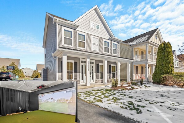 A two-story house with a covered porch, a garage, and a snow-covered lawn.