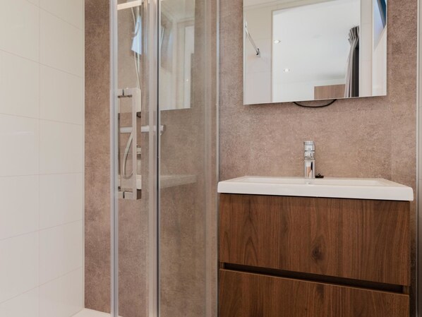 Une salle de bain moderne avec une douche à parois de verre, un meuble-lavabo en bois et un grand miroir au-dessus du lavabo.