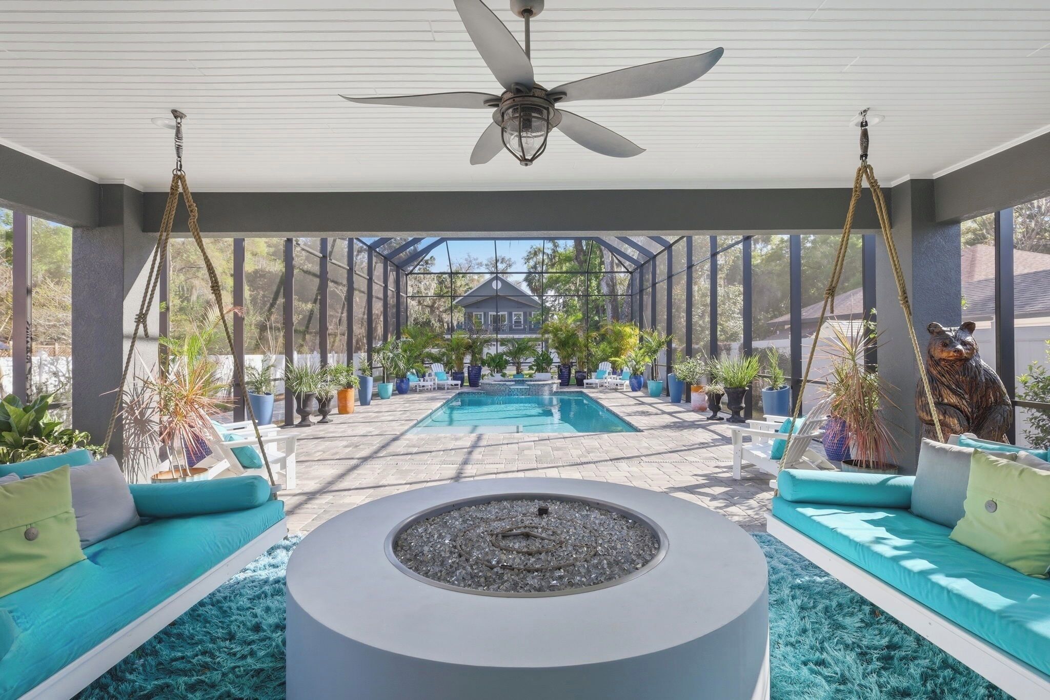 Un espacio al aire libre techado con piscina, asientos y ventilador de techo.