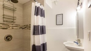 Un baño con ducha, lavabo y toallero.