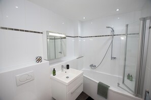 Features a sleek vanity, sink, and glass-enclosed shower area.