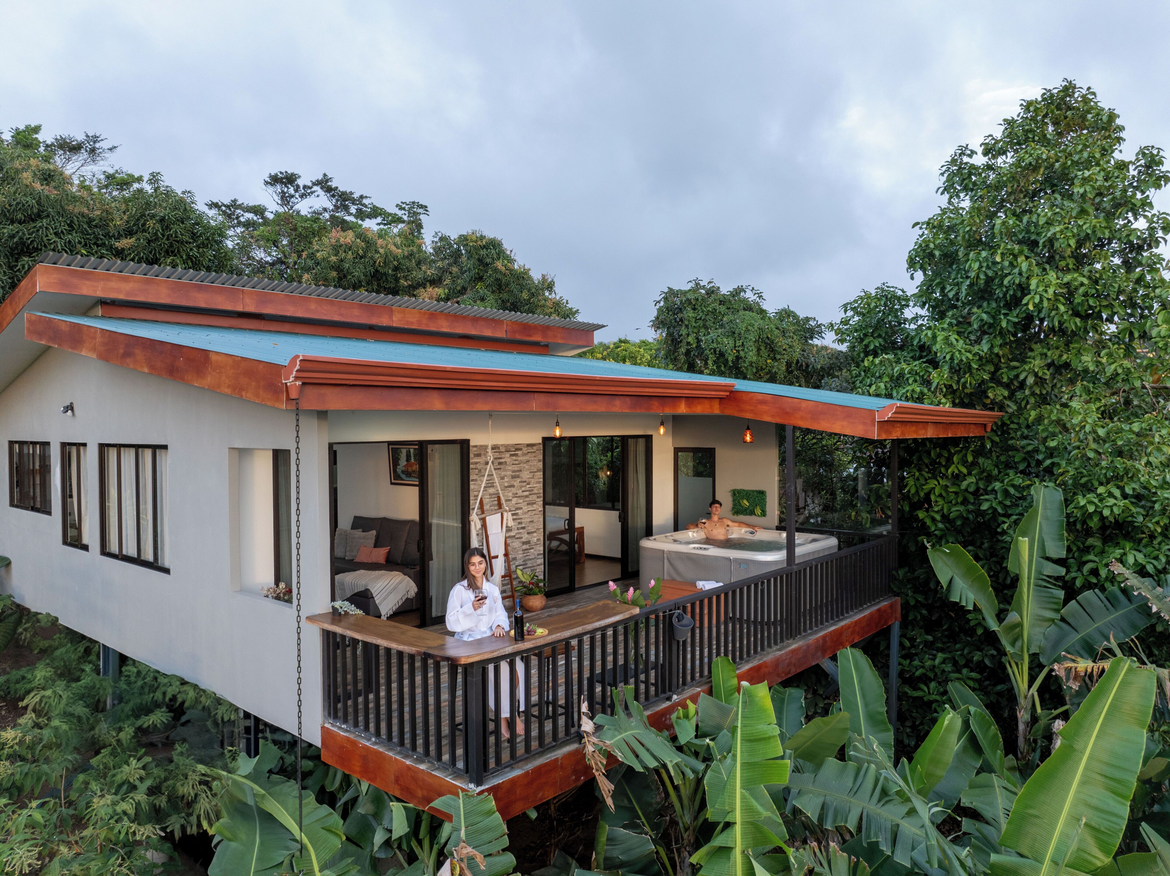 A modern house with a balcony, a hot tub, and a garden.