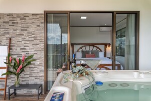 Un baño moderno con bañera, cabina de ducha de cristal y pared de piedra.