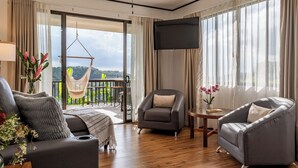 Un salon moderne comprenant un canapé, des fauteuils, une petite table, un fauteuil suspendu et un téléviseur fixé au mur.